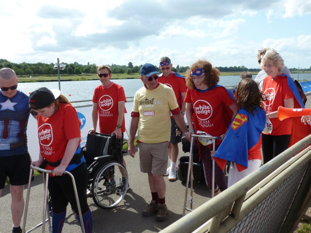The whole of Team Hannah walking across the finish line. Ami and Hannah with their zimmer frames and support.