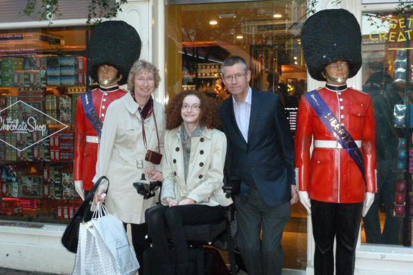 Hannah with her parents outside Libertys on her Starlight wish. Either side of her Mum and Dad there are two soldier statues (Queen's/King's Guards) with red jackets and black bearskin hats.