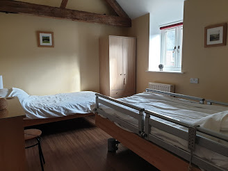A bedroom with one electric adjustable bed and one standard bed.