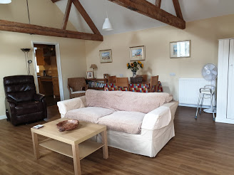 The lounge in Barnes cottage which has a sofa, leather arm chair and table and chairs in it.
