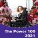 Hannah- a young woman with aburn curly hair and glasses, wearing leggings and a black leather jacket sitting in a powerchair surrounded by lots of pink and red flowers. A view over London in the background. There is a purple vector over the bottom of the photo which says: 'The Power 100 2021' in white on it.