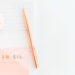 2023-What Are My Hopes? A pale pink gerbera laying on a pink card that says: 'Dream Big, Dream Often' on a white lined notebook and a rose gold pen overlapping the card.