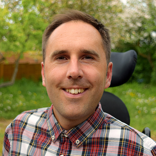 Martyn Sibley is one of the featured disabled bloggers and influencers. It shows his head and shoulders. He is wearing a red check shirt and smiling at the camera.