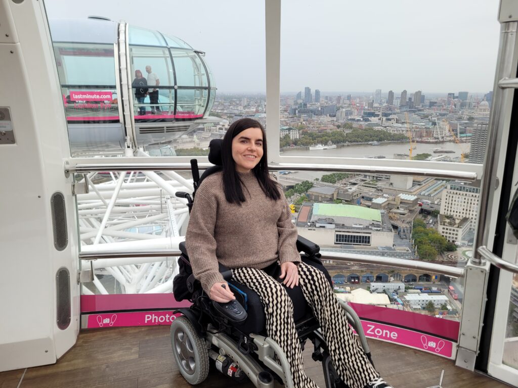 Emma Muldoon on of the featured disabled bloggers sitting in her powerchair in a capsule on a wheel, possibly the London Eye.