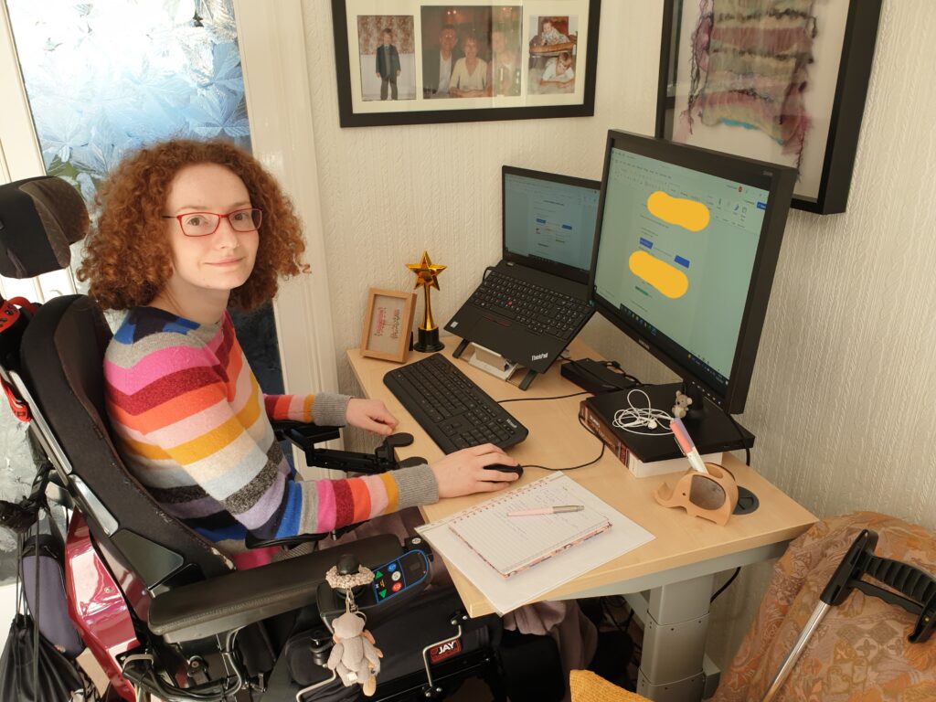 Hannah working from home at her desk with her laptop and monitor in front of her.