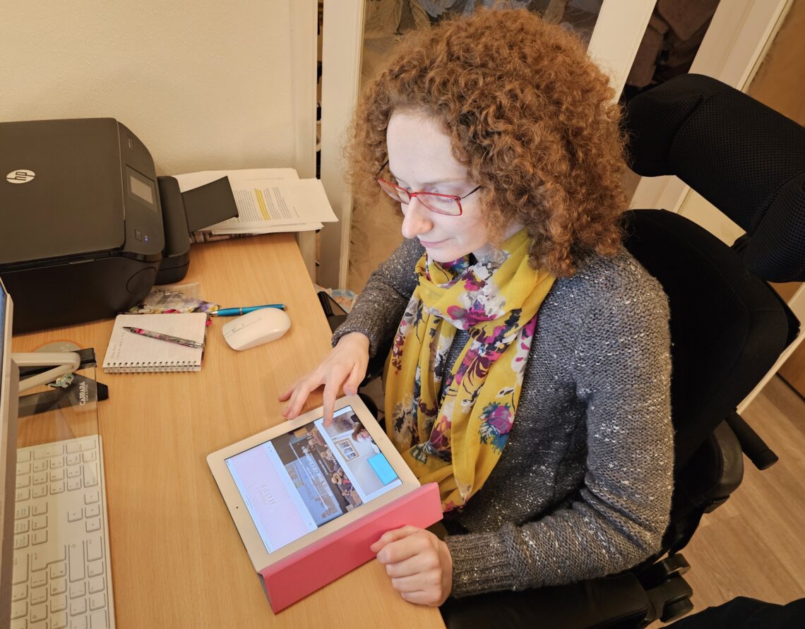 How To Start A Blog- Hannah looking at her blog on an iPad on the desk in front of her.
