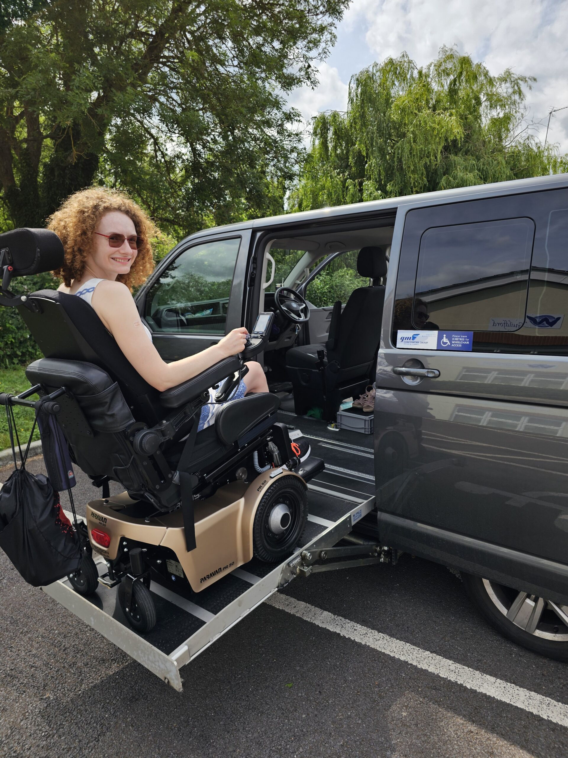 Hannah accessing her WAV using her powerchair via a side lift. The lift is halfway up before she enters. This is illustrating PIP a benefit that supports disabled people.