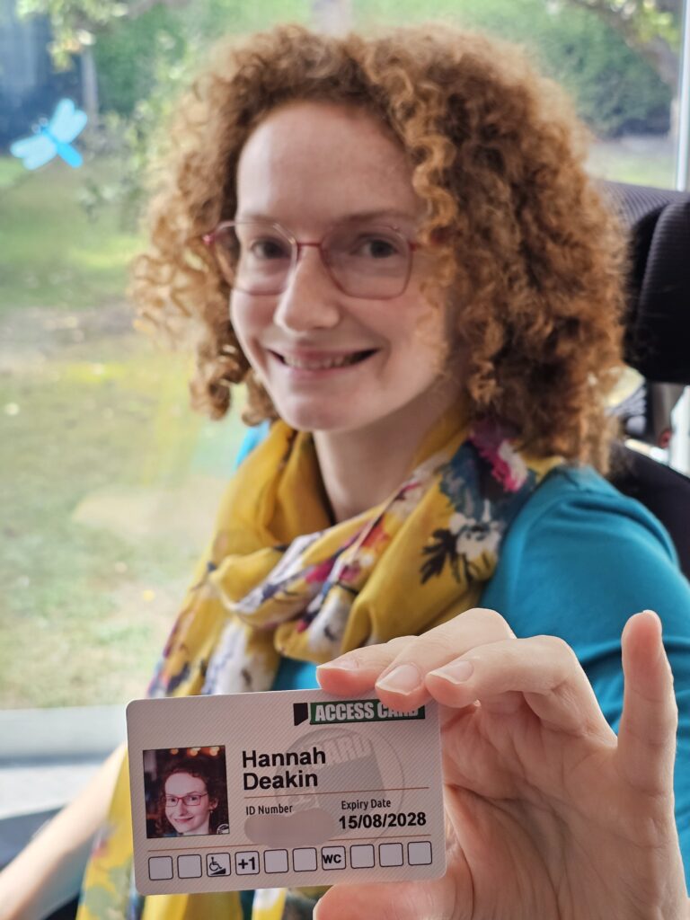 Hannah holding an Access Card. One of the six organisations disabled people should know about.